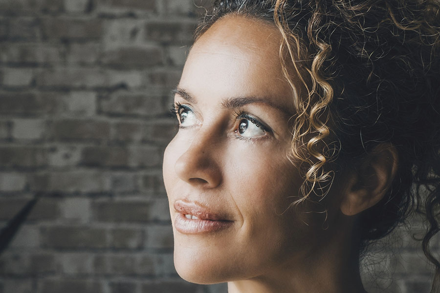 A close-up profile of a woman looking upward with a hopeful, calm expression, illustrating a survivor reclaiming peace and self-compassion after relationship trauma.