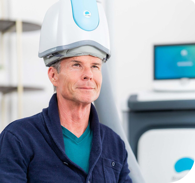 A man wearing a BrainWay helmet for specialized TMS therapy in Phoenix, AZ, in a clinical setting.