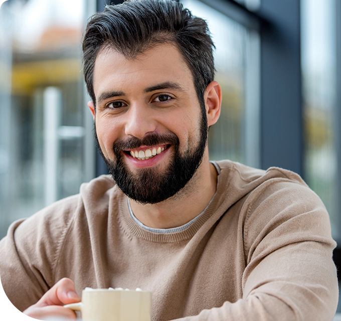 A smiling man with a cup, illustrating a successful rehab in another state in a bright setting.
