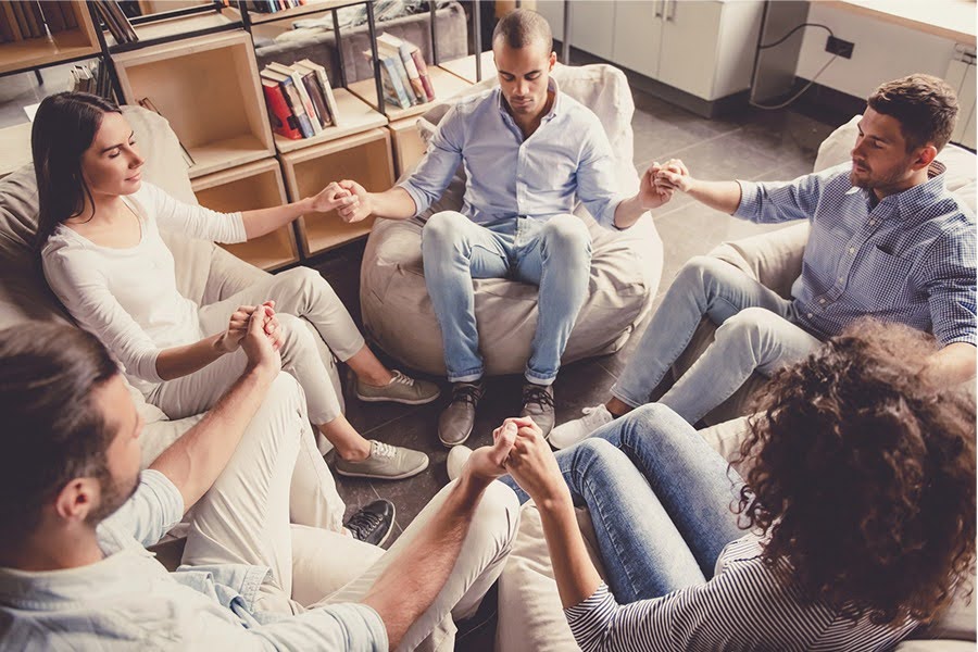 A support group holding hands in a circle during an intensive outpatient program Phoenix session.