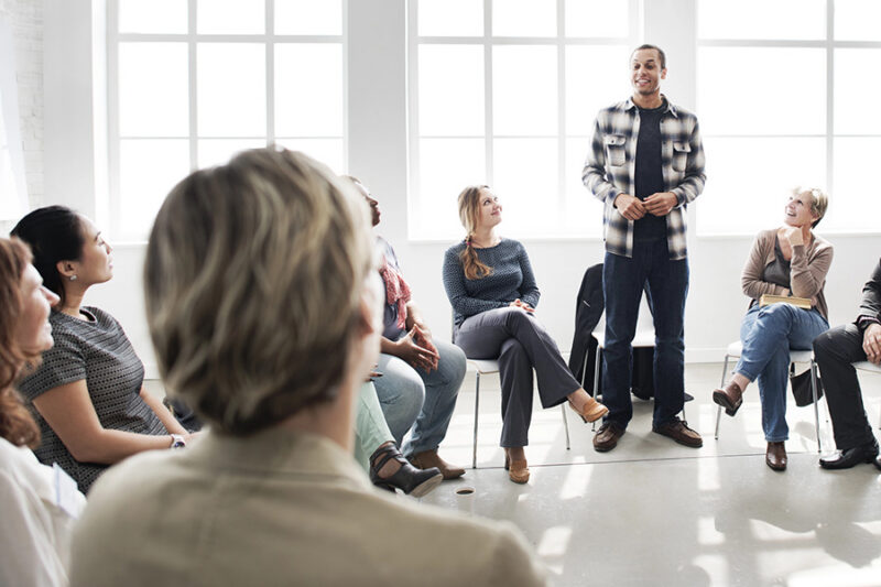 A supportive group therapy session in a bright, modern setting as part of an out-of-state treatment program.