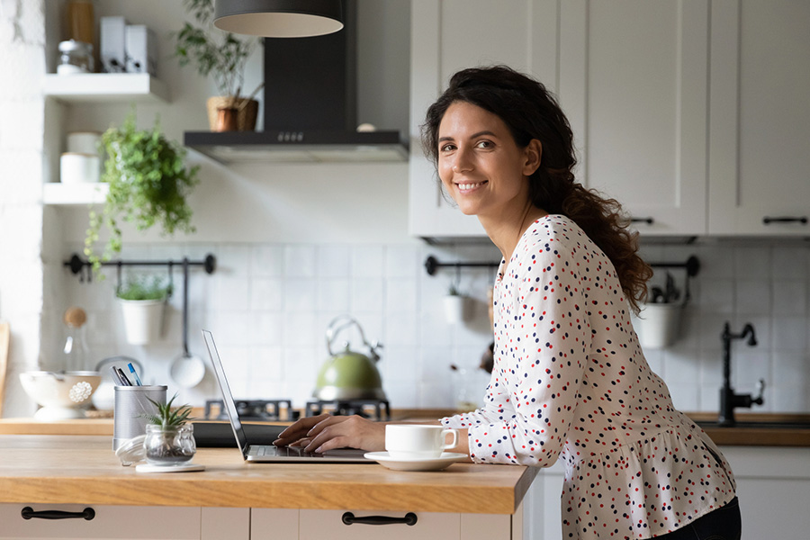 A woman smiling at her laptop, relieved after verifying their out of state rehab insurance coverage for treatment.