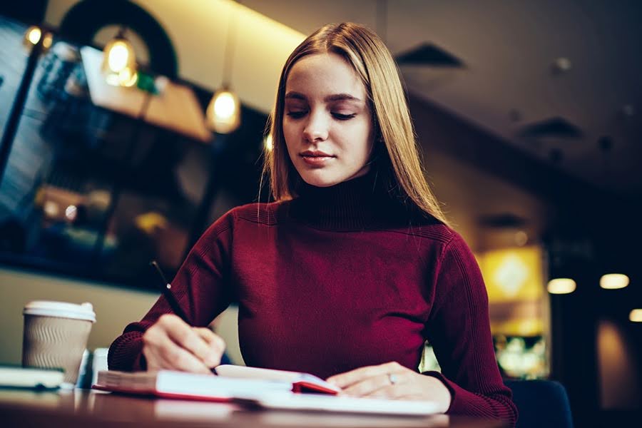 A young woman writing in a journal, reflecting on her partial hospitalization program stabilization journey.