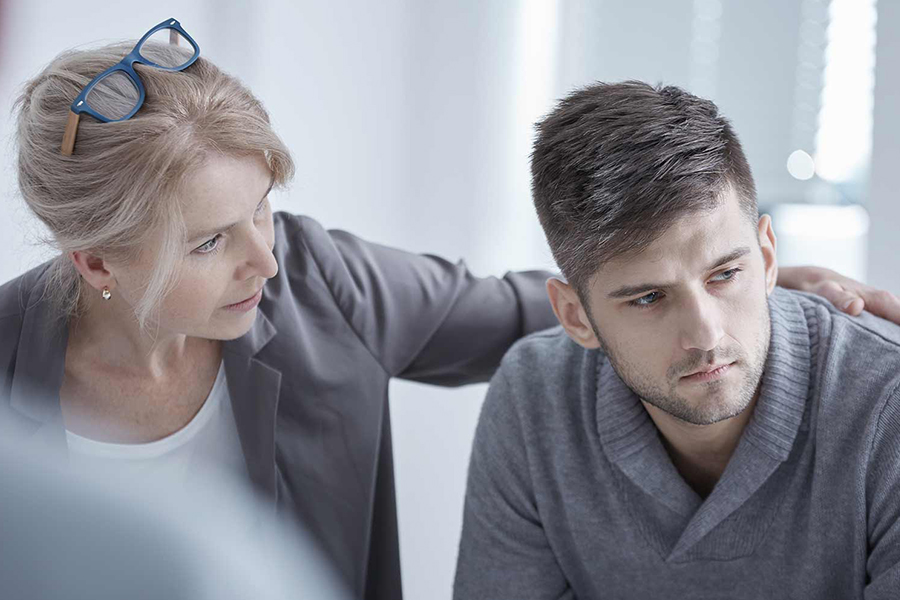 Adult female providing consoling a man struggling with mental health disorder and substance abuse disorder, as they seek help.