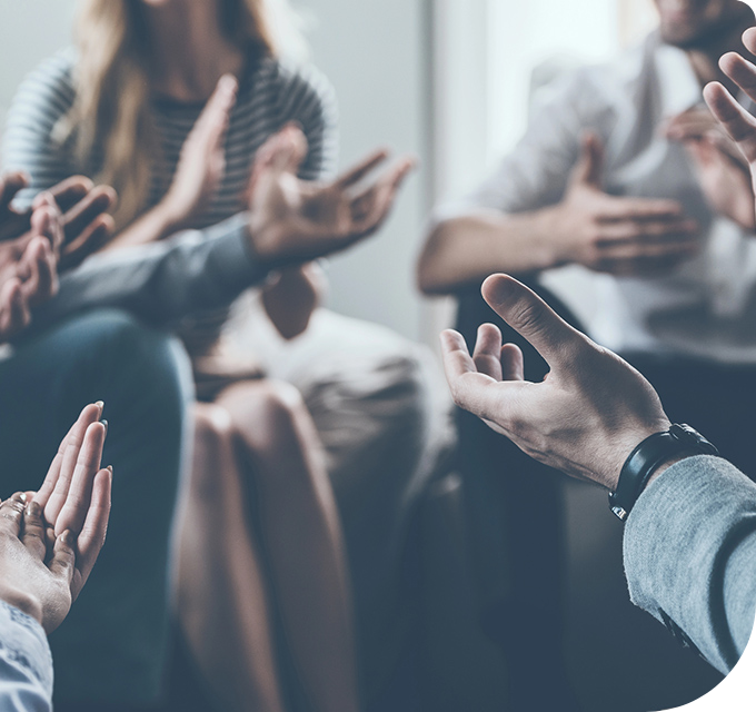 Close-up of diverse hands in a circle clapping, representing peer support for Colorado residents in rehab.