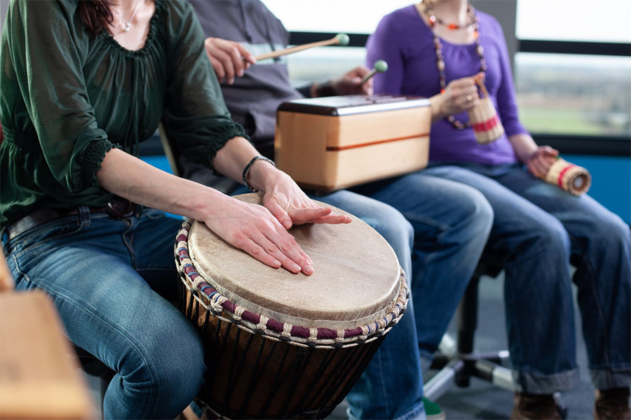 Group of people playing musical instruments during recreational therapy for addiction and mental health treatment.