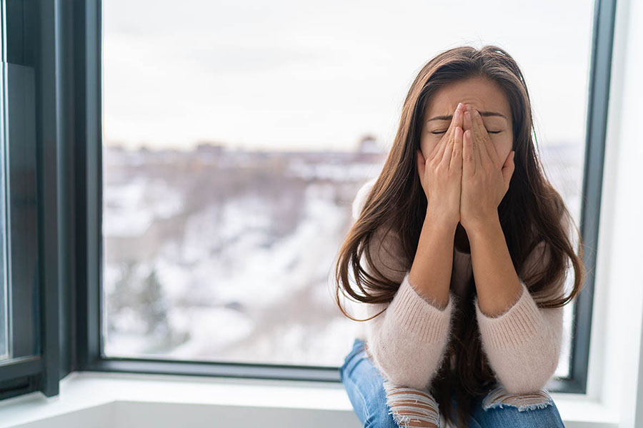 Woman with anxiety sitting, hands covering face – Depicting the mental health impact of childhood trauma on individuals’ emotional well-being. Woman with anxiety sitting, hands covering face - Depicting the mental health impact of childhood trauma on individuals' emotional well-being.