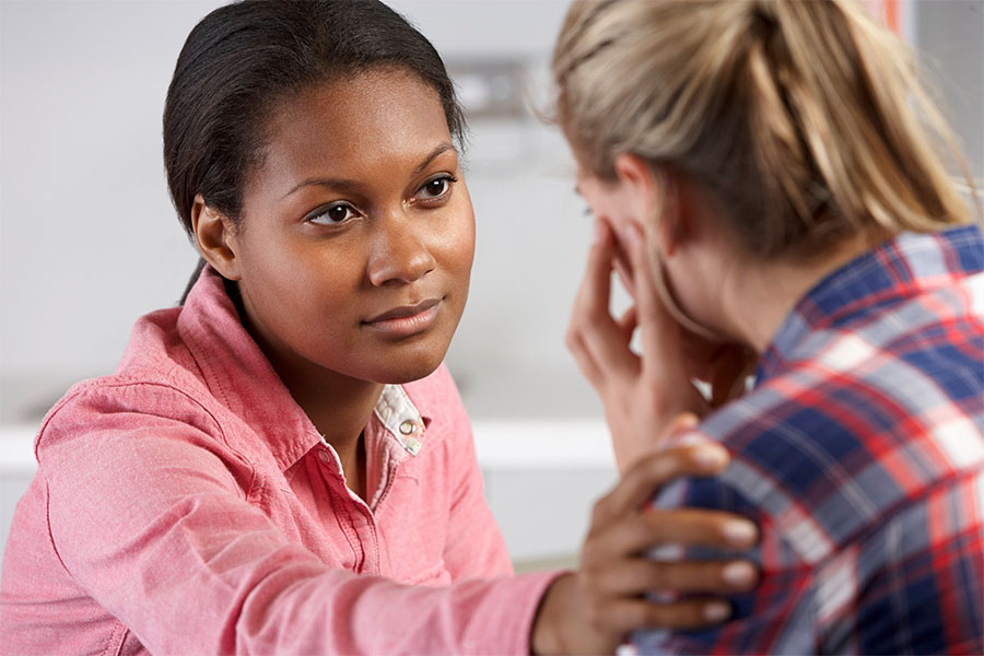 Young lady comforting her friend. Listening is the number one step on how to help someone with major depressive disorder.