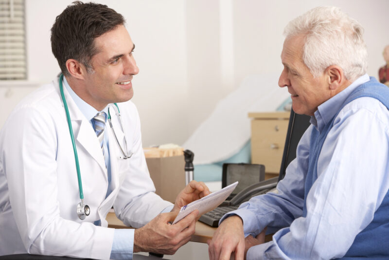 Doctor speaking with an older patient during a consultation, discussing options for cognitive decline treatment in a supportive clinical setting