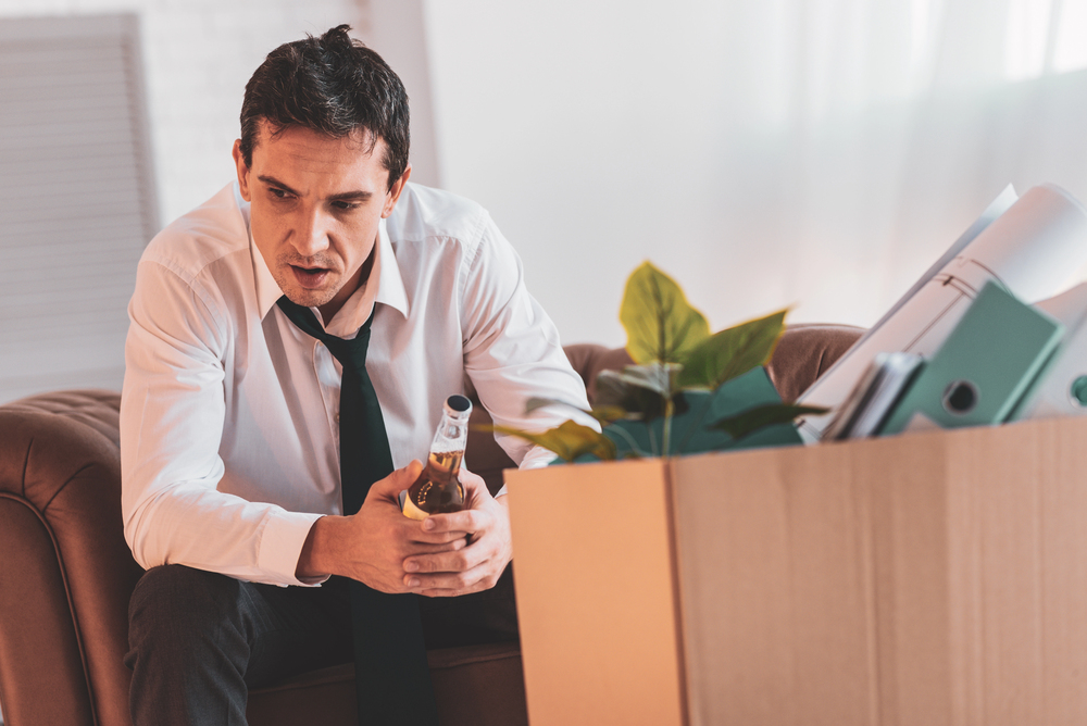 A stressed businessman holding a beer bottle, illustrating high functioning alcoholic signs