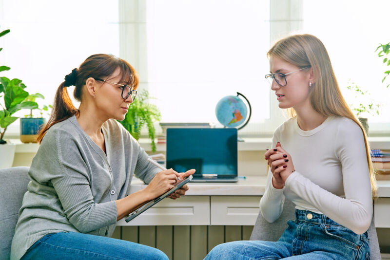 A therapist using motivational interviewing for addiction while listening to a young woman during a counseling session