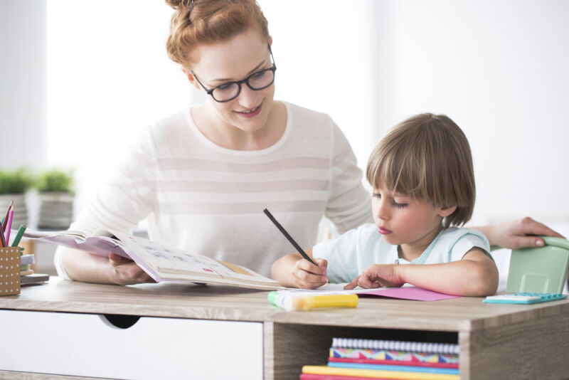 Teacher guiding a young child with writing activities, symbolizing conditions found in a neurodivergent list