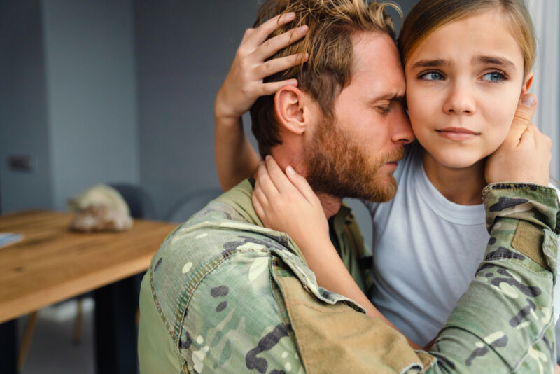 Emotional embrace between a soldier and a young girl, symbolizing family healing from a veterans rehabilitation center